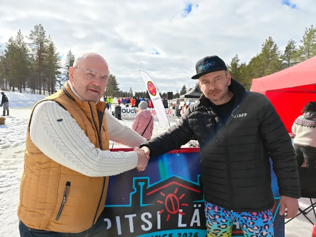 Datavoiman Matti Lassila ja Pitsi Events ry:n Tuomas kättelevät tapahtumapaikalla Pitsi Lätkä -tapahtuman kyltin edessä