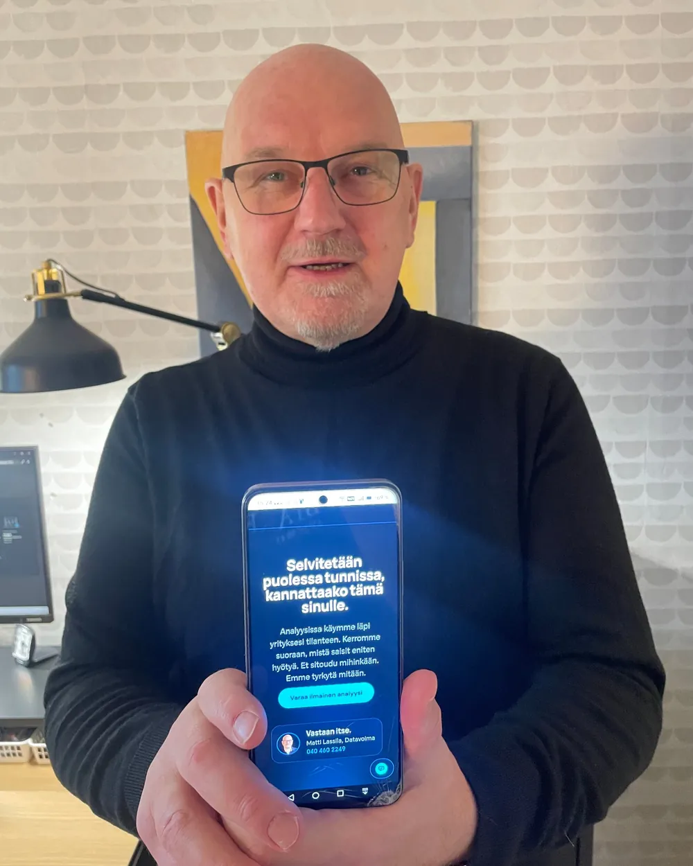Matti Lassila näyttää puhelimelta Datavoiman sivua, jolta voi varata ilmaisen analyysin